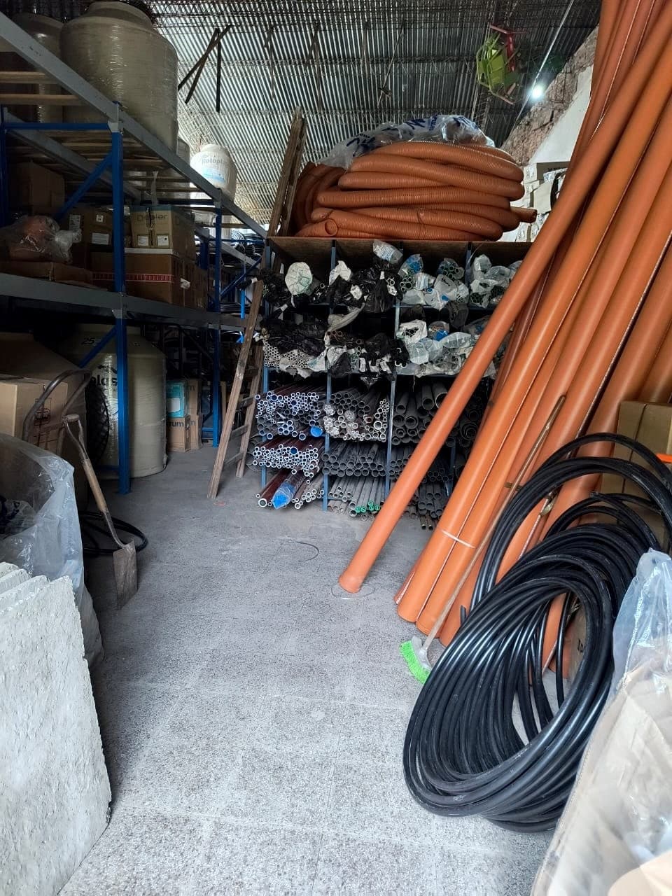 Depósito de SANITARIOS ESCOBAR con caños, rollos de manguera y conexiones en estanterías