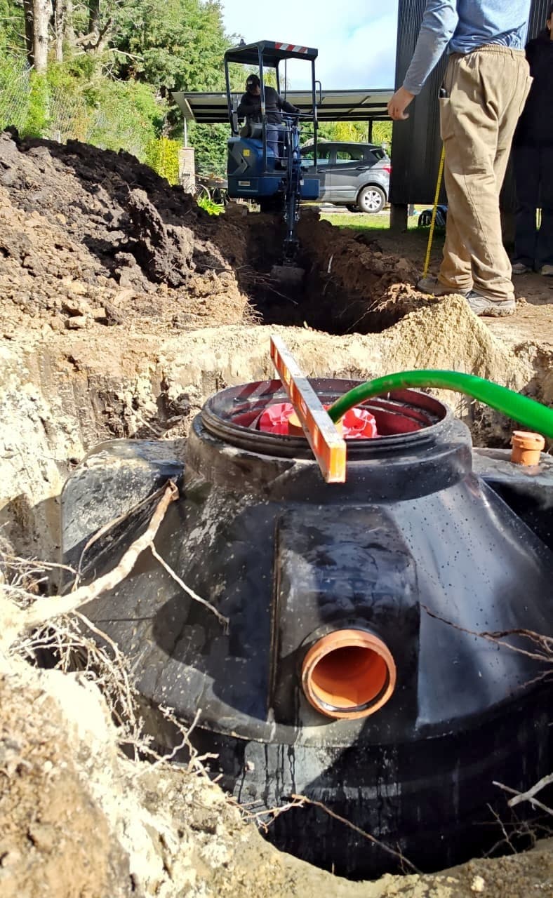 Biodigestor BIO.360 instalado en el pozo, con las conexiones de entrada y salida, y la retroexcavadora atrás